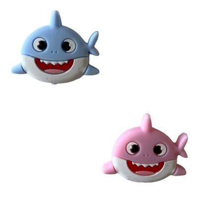 Dois brinquedos de tubarão sorridente, azul e rosa, fundo branco