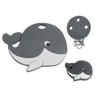 Conjunto para bebé com dois mordedores de silicone em forma de baleia cinzenta e branca e um clip metálico redondo cinzento.