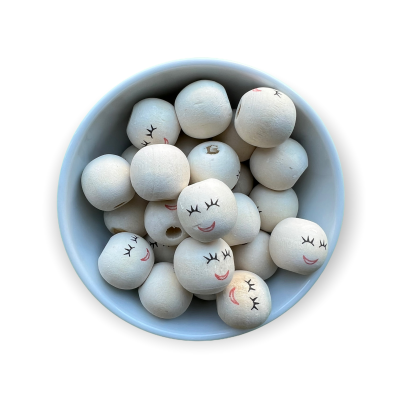 Contas de madeira brancas com rostos desenhados dentro de um recipiente branco.