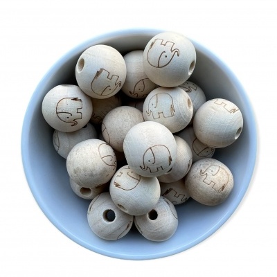 Bolas de madeira claras com desenhos de elefantes gravados numa tigela branca