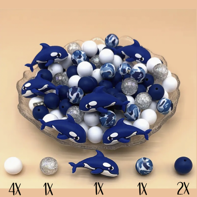 Contas decorativas em azul, branco, transparente, incluindo orcas azuis numa taça transparente