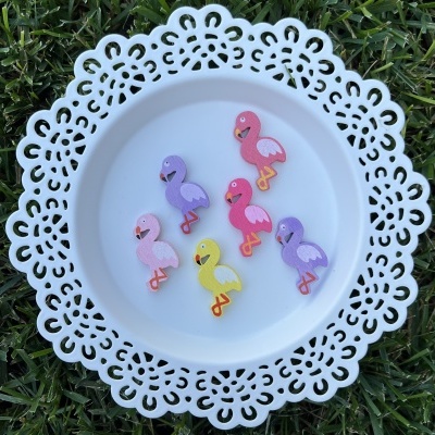 Ornamentos de flamingos coloridos em prato branco rendado sobre relva