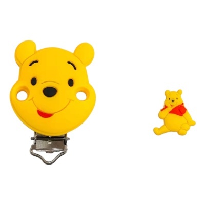 Dois acessórios amarelos do Winnie the Pooh, clip em forma de cabeça sorridente e pequena figura sentada com camisola vermelha.