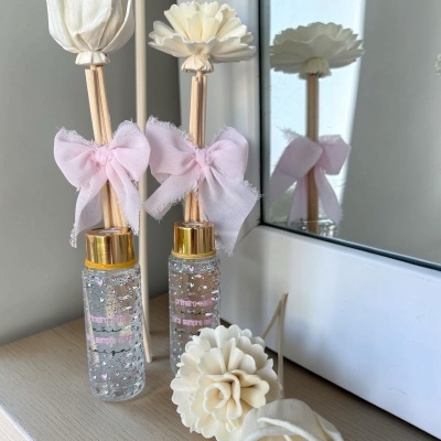 Frasco decorativo com flores artificiais e fita cor-de-rosa junto a espelho