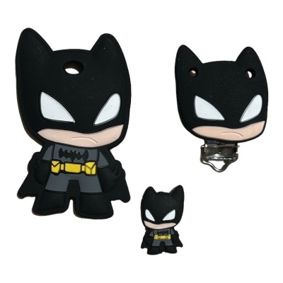 Três acessórios em forma de personagem de Batman estilizado, em silicone e plástico, com cores preta, cinzenta, amarela e branca.