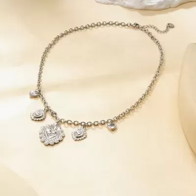 Colar prateado com pendentes de coração sobre superfície bege clara