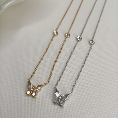 Colares dourado e prateado com pendentes em forma de borboleta sobre fundo branco.