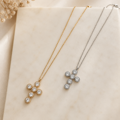 Dois colares com pendentes em forma de cruz, um dourado e outro prateado, com cristais redondos.