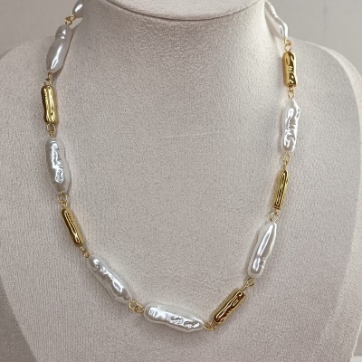 Colar de pérolas brancas e contas douradas em busto bege