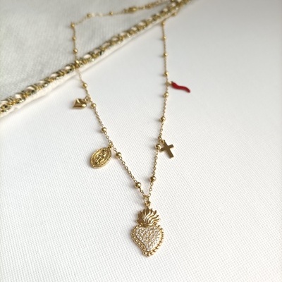 Colar dourado com vários pendentes sobre tecido branco