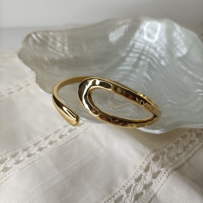 Pulseira dourada em prato branco translúcido sobre tecido claro com renda