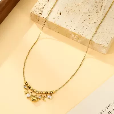 Colar dourado com pendentes variados sobre superfície amarela