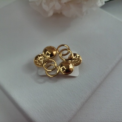 Brincos dourados com design circular e textura variada sobre tecido branco.