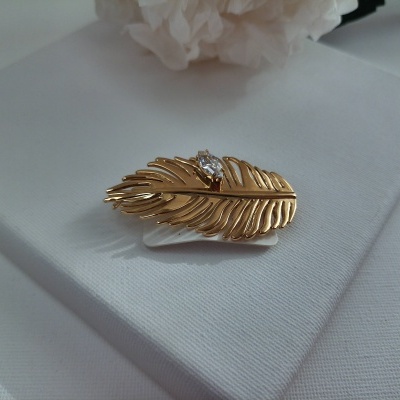 Prendedor de cabelo dourado em forma de pena com pedra branca