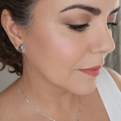 Mulher a usar brincos e colar prateados com pendente