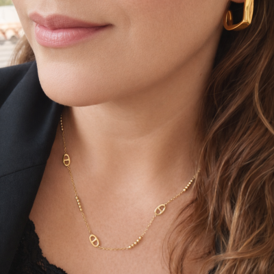 Colar e brinco dourados em metal com design geométrico usados por mulher.