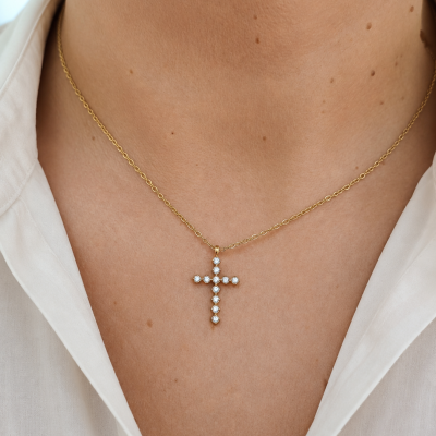 Colar dourado com pendente cruz de pedras brilhantes no pescoço