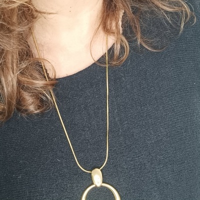 Colar dourado com pendente circular liso em camisa preta