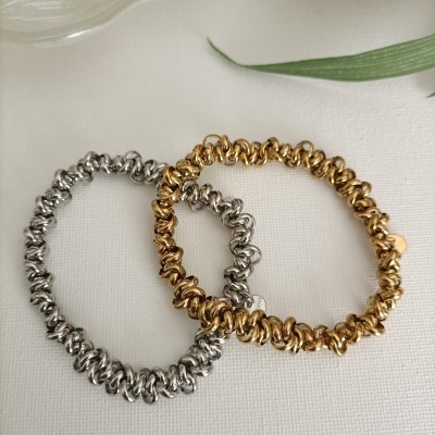 Braceletes dourado e prateado de argolas metálicas sobre tecido branco