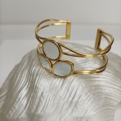 Bracelete dourado com pedras claras em superfície texturizada branca