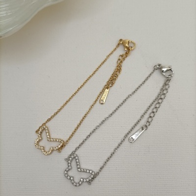 Dois colares com pendentes de borboleta em metal dourado e prateado sobre fundo branco.