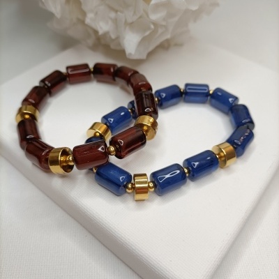 Duas pulseiras com contas castanhas e azuis translúcidas com detalhe dourado sobre fundo branco