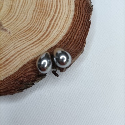 Brincos em metal prateado sobre disco de madeira