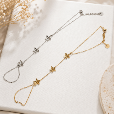 Duas pulseiras finas de metal com flores decorativas sobre superfície branca