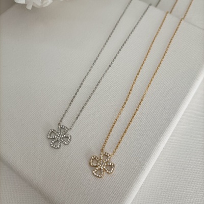 Dois colares com pendente em forma de flor sobre superfície branca