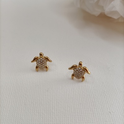 Brincos de tartaruga dourada com pedras brilhantes sobre fundo branco