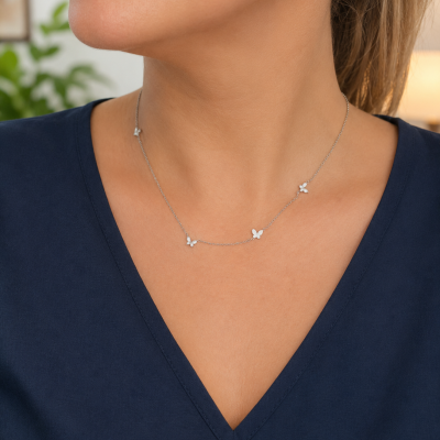 Colar prateado com borboletas num pescoço feminino com blusa azul escura