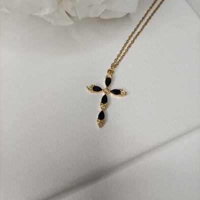 Colar dourado com pendente em forma de cruz com pedras pretas e brilhantes.
