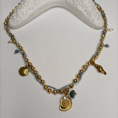 Colar azul com contas douradas e pendentes de conchas perto de estrela do mar branca