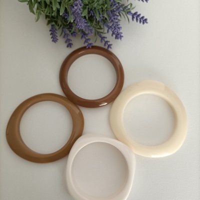 Quatro pulseiras de resina castanho, bege e branco com flores lilases.