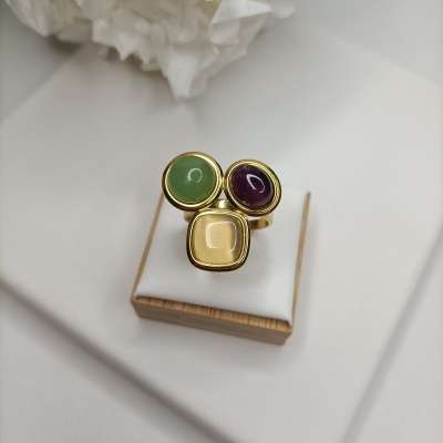 Anel dourado com três pedras coloridas em suporte branco