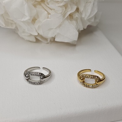 Dois anéis ajustáveis, um prateado e outro dourado, com pedras brilhantes, num fundo branco.