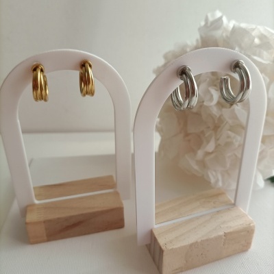 Brincos de argola duplos dourados e prateados em suportes brancos com base de madeira