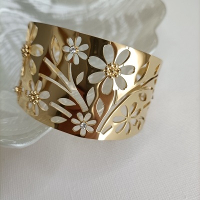 Bracelete dourado com flores recortadas e cristais em fundo branco