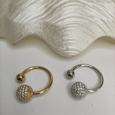 Par de brincos dourado e prateado com esferas cravejadas em fundo branco com concha