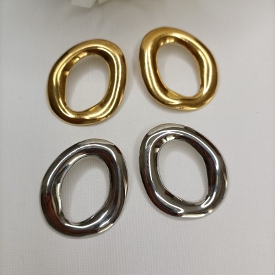 Quatro argolas metálicas irregulares, duas douradas e duas prateadas, com fundo branco e flor branca