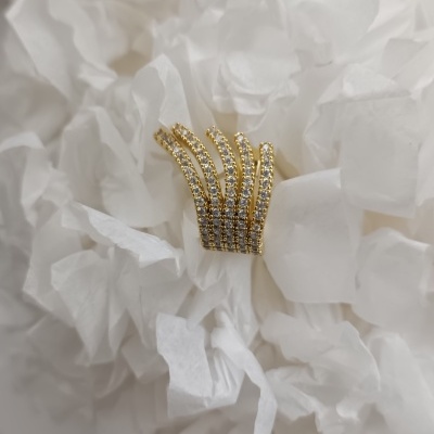 Anel dourado com pedras brilhantes sobre papel branco amassado