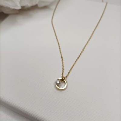 Colar dourado com pendente circular e pérola em fundo branco