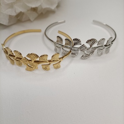 Duas pulseiras com folhas dourada e prateada sobre fundo branco