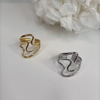 Dois anéis metálicos dourado e prateado com design ondulado sobre tecido branco.