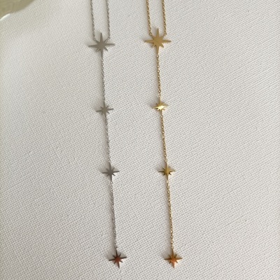 Colares finos de metal com estrelas em prata e dourado sobre tecido branco