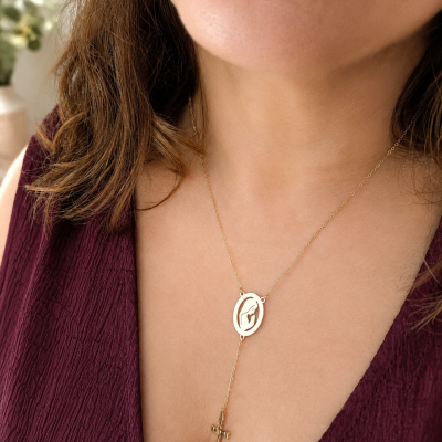 Colar dourado com pendente oval e cruz pendente, usado no pescoço