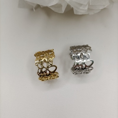 Dois anéis metal dourado e prateado com padrão de borboletas sobre superfície branca