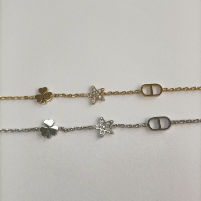 Duas pulseiras metálicas com trevo, estrela com pedras e emblema CD.