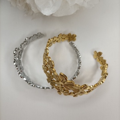 Dois braceletes metálicos, dourado e prateado, com flores em relevo.