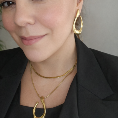 Colar e brinco dourados com design irregular usados por mulher